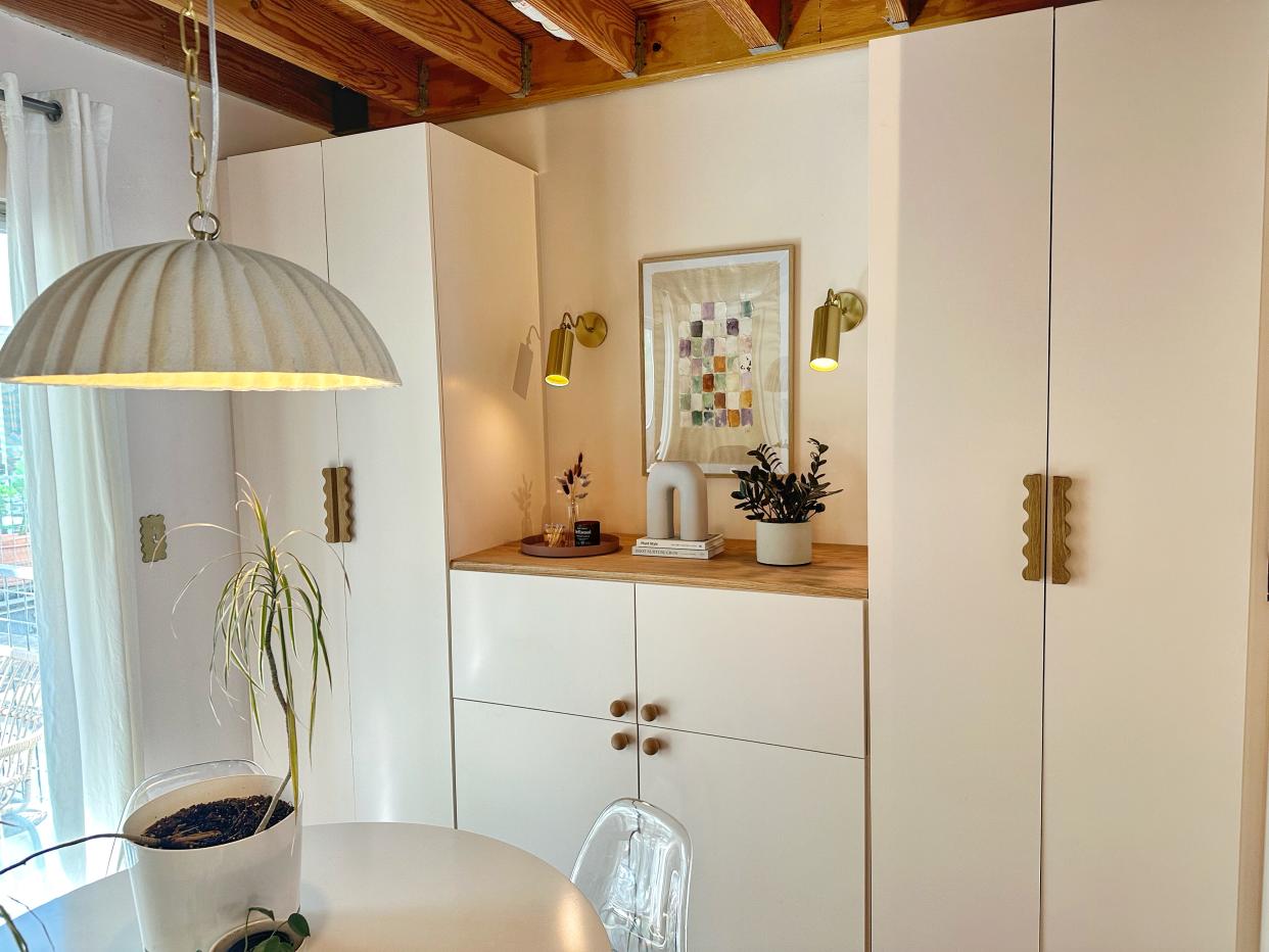  An IKEA BESTA unit with two PAX closets to make built-in wall storage and decorated with decor and houseplants. 