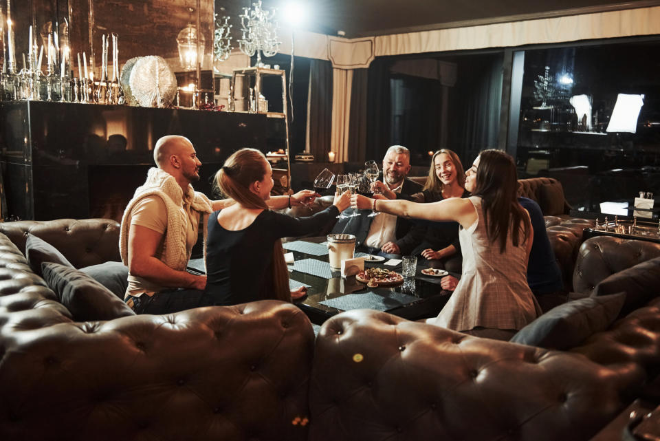 Group of friends toasting with wine glasses around a table in a cozy setting