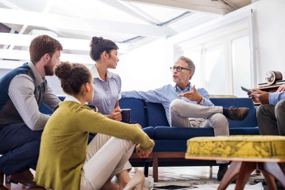 A mature businessman talking with young colleagues in a creative office