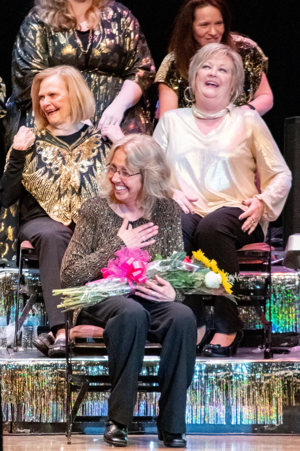 Karen Boyer receives flowers and a round of applause on stage after being recognized as the music director for the Cambridge Lions Club 50th anniversary Music and Comedy Show.