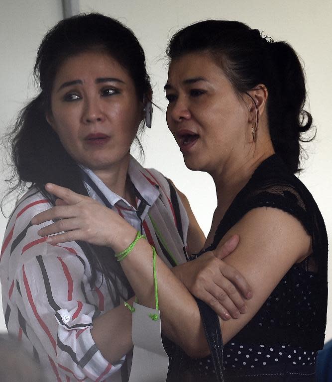 Relatives of passengers onboard the missing AirAsia flight QZ8501 react to news of floating debris spotted in the search for the plane, as they wait at a crisis-centre set up at Juanda International Airport in Surabaya, on December 30, 2014