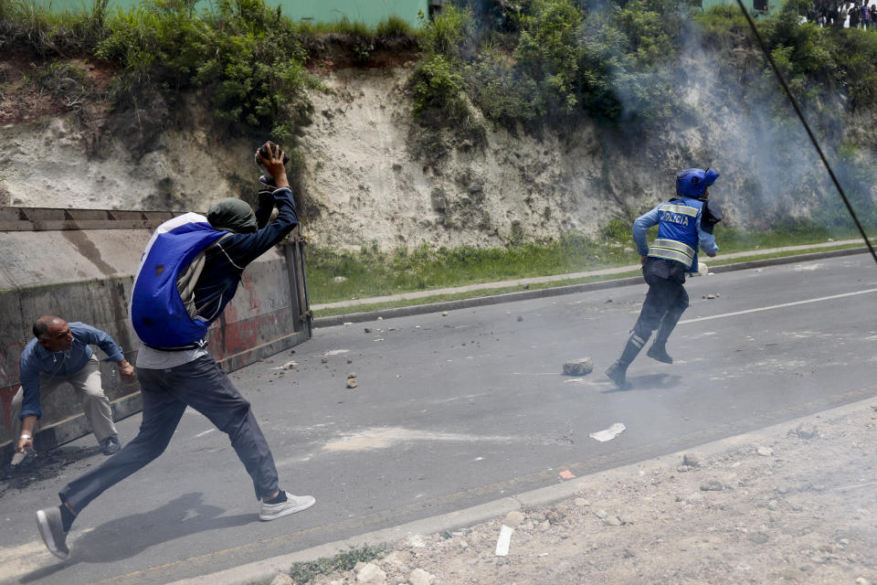 A police officer runs away as demonstrators charge and throw rocks at him during a protest against the government of Honduras' President Juan Orlando Hernandez in Tegucigalpa, Honduras, Thursday, May 30, 2019. Thousands of doctors and teachers have been marching through the streets of Honduras' capital for the las three weeks, against presidential decrees they say would lead to massive public sector layoffs. (AP Photo/Elmer Martinez)