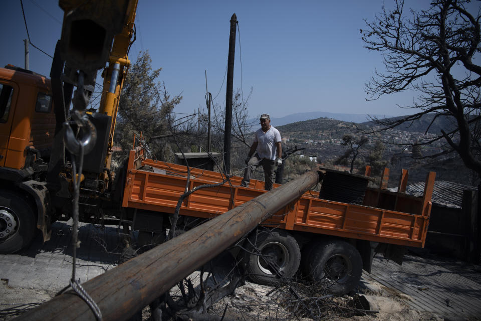 Workers of the electric company replace a utility pole after a wildfire in the Fyli suburb, northwest Athens, Greece, Friday, Aug. 25, 2023. Authorities battling a major wildfire in northeastern Greece that has been described as the European Union's largest single fire recorded have recovered another body, the fire department says, bringing the total death toll of wildfires in Greece this week to 21. (AP Photo/Michael Varaklas)