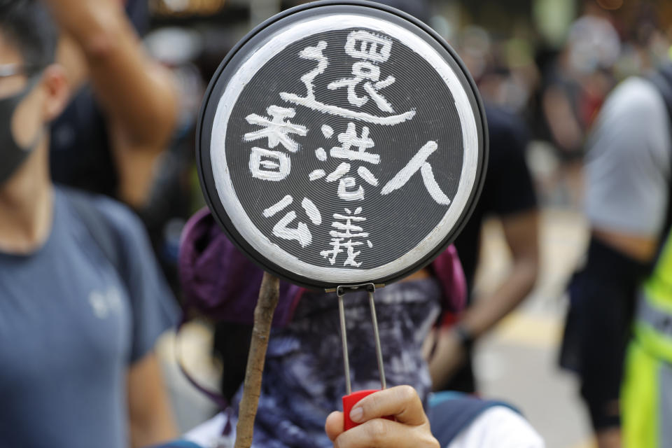 A protester holds up a cooking pan with the words "Return Hong Kong People Justice" written on the base in Hong Kong on Saturday, Oct. 5, 2019. All subway and trains services are closed in Hong Kong after another night of rampaging violence that a new ban on face masks failed to quell. (AP Photo/Vincent Thian)