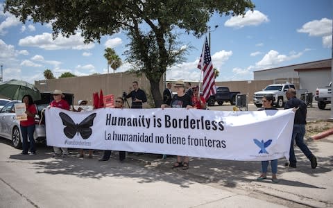 Demonstrators hold a large banner that reads "Humanity Is Borderless," outside of a U.S. Border Patrol station in McAllen, - Credit: Bloomberg