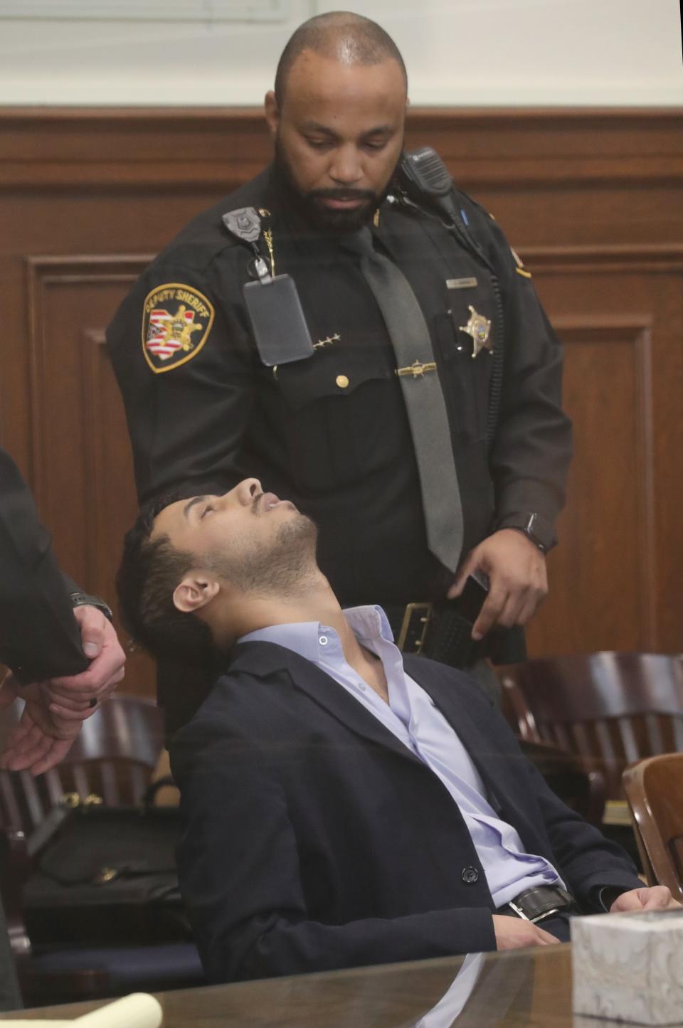 A Summit County Sheriff's deputy tends to defendant Mohamed Reeda after he fell ill during the reading of a split verdict Monday in Akron.