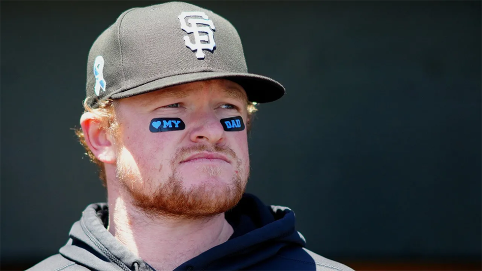 Un aficionado del baseball con unos dibujos en su rostro que dicen: "amo a mi padre".