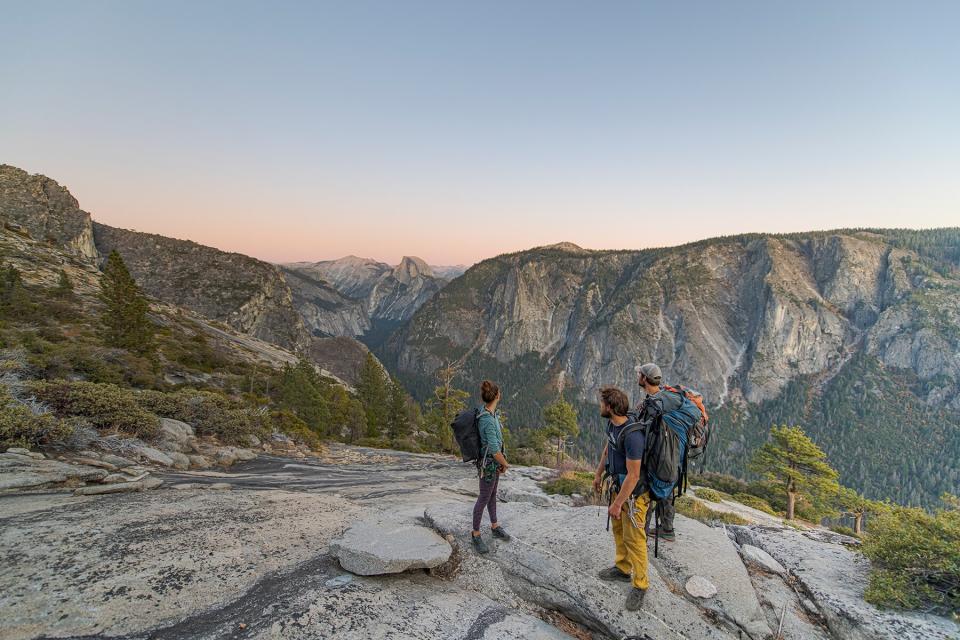 Three hikers looking at Half Dome from El Capitan sunset Yosemite