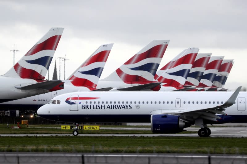 BA plane taxis past tail fins of parked aircraft to runway near Terminal 5 at Heathrow Airport