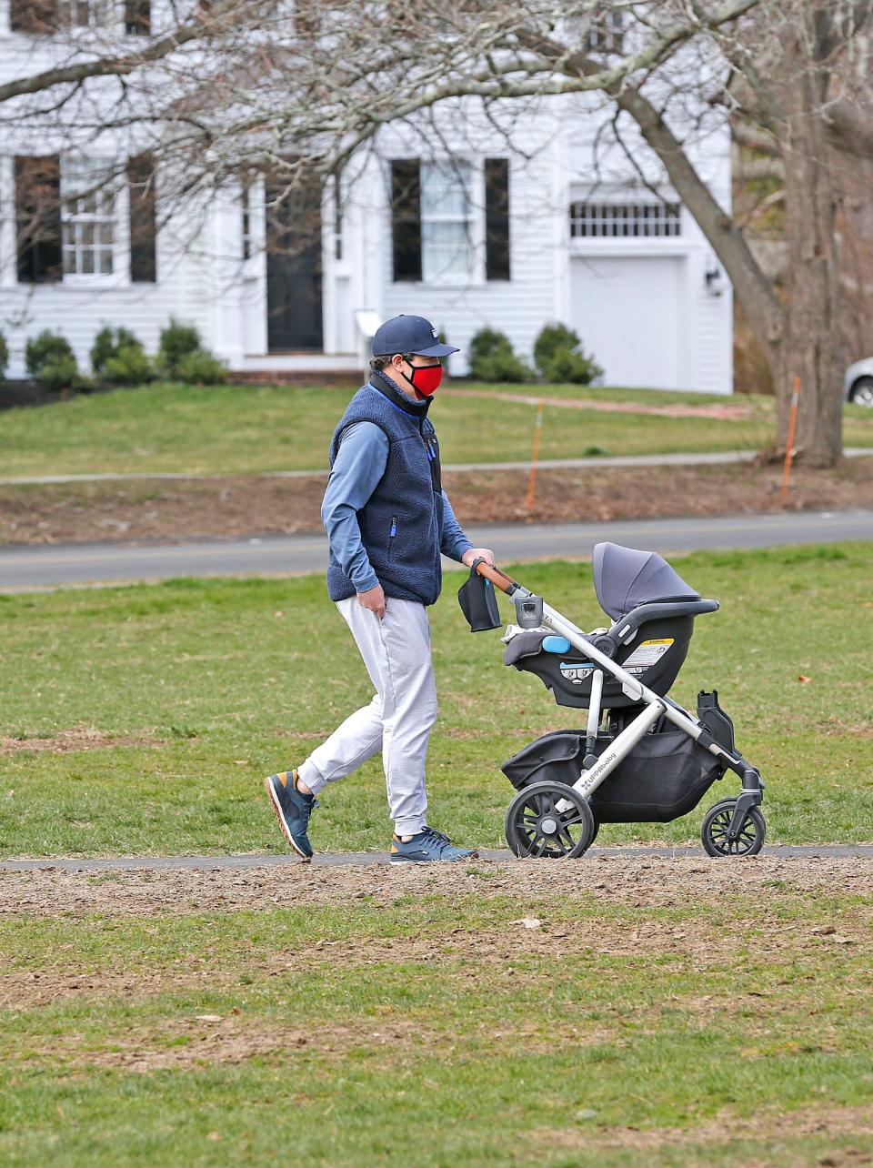 A man wears a mask while out for a walk with his child on Cohasset Common on Tuesday, April 6, 2021.