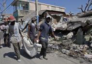 <p>Men carry the body of 24-year-old Sergeline Joseph after they were paid by her father Thomas Silvain, rear left, more than US$200 to retrieve her from the rubble of their collapsed house instead of waiting for demolition crews, in Port-au-Prince, Tuesday, Feb. 2, 2010. (Photo: Andres Leighton/AP) </p>