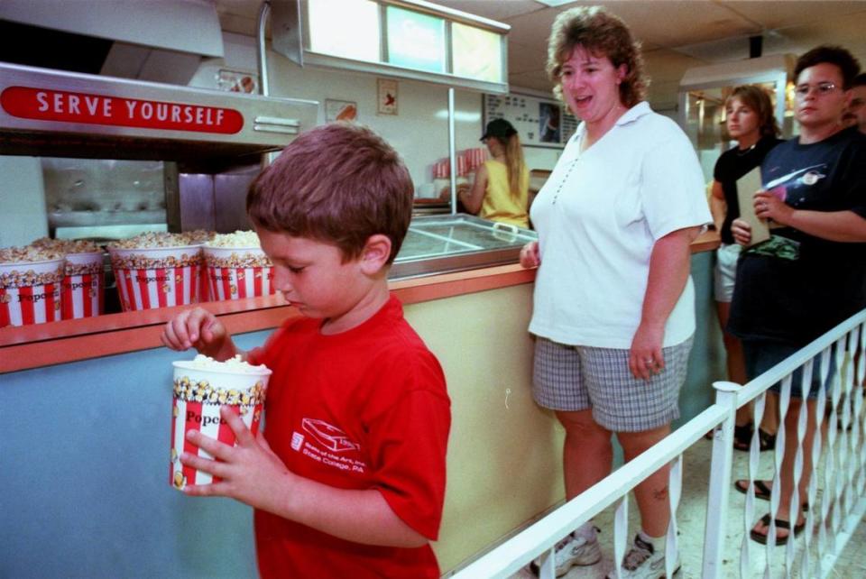 Levi Kelley gets an early start on his popcorn as his mother Jen Kelley of Tyrone looks on before watching a movie at the Starlite Drive-In Theatre on Saturday, July 31, 1999.