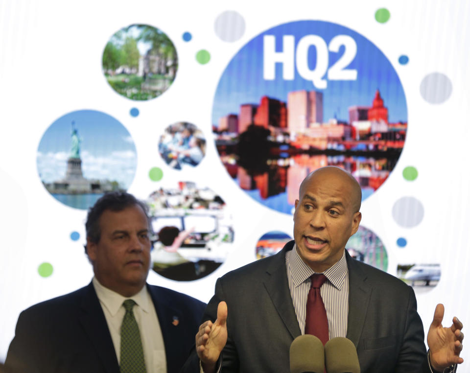 FILE - In this Oct. 16, 2017, file photo, New Jersey Sen. Cory Booker, right, speaks while New Jersey Gov. Chris Christie stands behind him during an announcement in Newark, N.J. Officials in Newark, which was one of the 18 finalists that Amazon rejected in November when it announced it would split its HQ2 between New York and northern Virginia, sent a giant heart that said “NJ & Newark Still Love U, Amazon!” The love note came despite Amazon saying it’s not seeking a new site. (AP Photo/Seth Wenig, File)