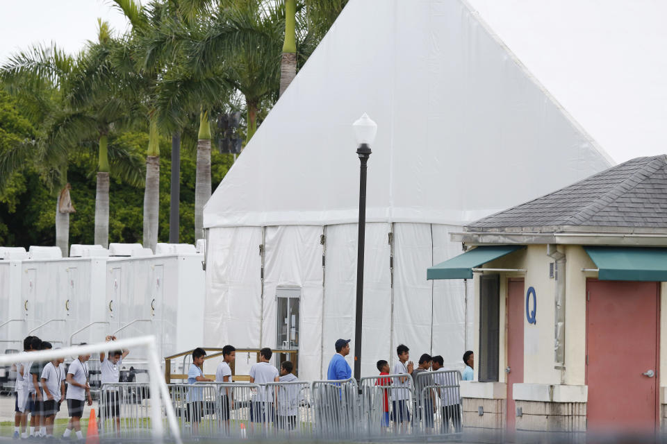 FILE - In this Wednesday, June 20, 2018 file photo, immigrant children walk in a line outside the Homestead Temporary Shelter for Unaccompanied Children, a former Job Corps site that now houses them, in Homestead, Fla. Nearly every adult working with children in the U.S. _ from nannies to teachers to coaches _ has undergone state screenings to ensure they have no proven history of abusing or neglecting kids. One exception: thousands of workers at this and another federal detention facility holding 3,600 migrant teens in the government’s care, The Associated Press has learned. (AP Photo/Brynn Anderson)