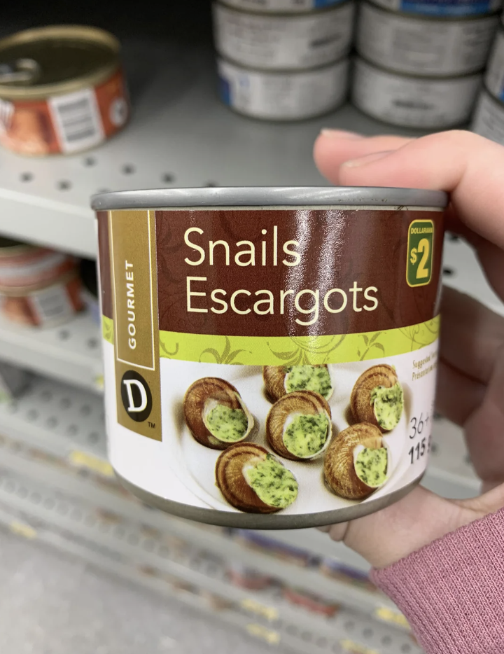 Hand holding a can labeled "Snails Escargots" on a store shelf; price tagged at $2