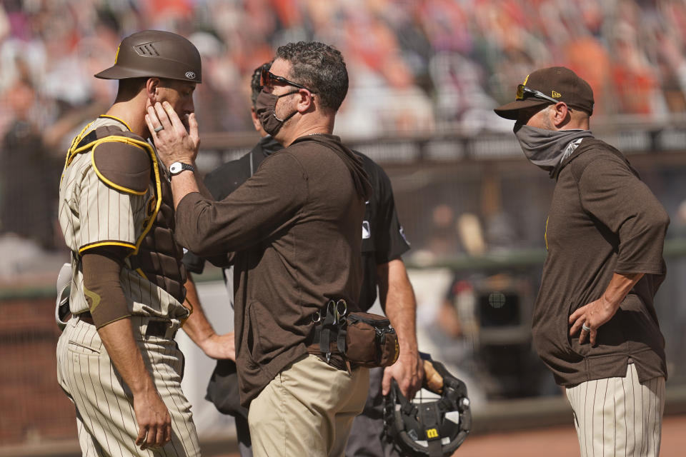 San Diego Padres catcher Jason Castro, left, is checked by a trainer as manager Jayce Tingler, right, looks on in the sixth inning of a baseball game against the San Francisco Giants, Sunday, Sept. 27, 2020, in San Francisco. Castro left the game and was replaced by Austin Nola. (AP Photo/Eric Risberg)