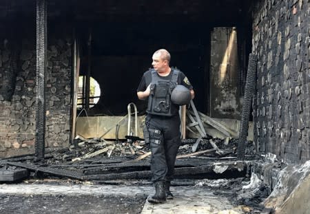 A law enforcement officer walks at a site of a burnt house, which is reportedly owned by former Governor of the Ukrainian Central Bank Valeria Gontareva, in Kiev