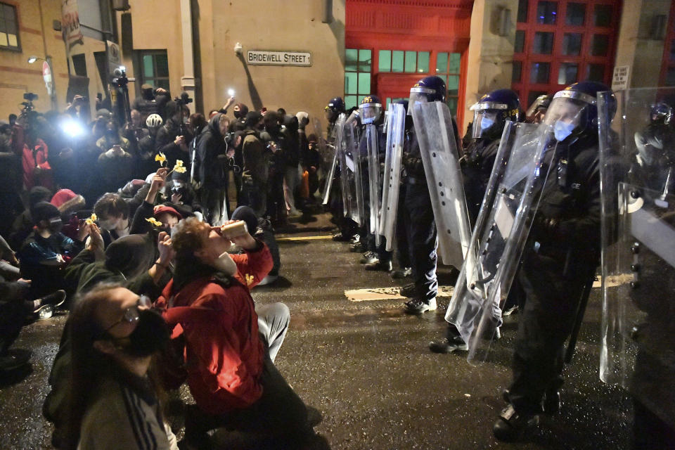 Protesters sit in front of police officers during the "Kill The Bill" protest in Bristol, England, Friday, March 26, 2021. Protesters are calling to protect free speech and protesting against new powers to be given to the police to impose conditions on non-violent protests, including those deemed too noisy or a nuisance. (Ben Birchall/PA via AP)