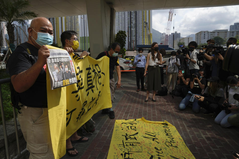 Pro-democracy activists holding a copy of Apple Daily newspaper and banner protest outside a court in Hong Kong, Saturday, June 19, 2021, to demand to release political prisoners. The top editor of the Hong Kong's pro-democracy newspaper and the head of its parent company were brought to a courthouse Saturday for their first hearing since their arrest under the city's national security law.(AP Photo/Kin Cheung)