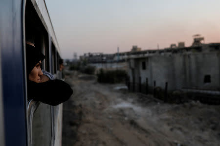 A woman looks out of a window of a train traveling through the outskirts of Damascus towards recently opened international fair in Damascus, Syria, September 12, 2018. REUTERS/Marko Djurica/Files