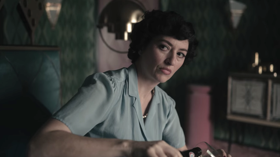 Marielle Heller as Alma Wheatley pours herself a drink in front of her daughter in "The Queen's Gambit"