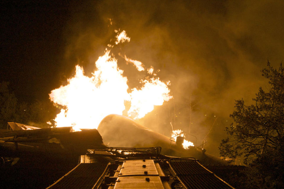 Flames rise from a derailed freight train early Wednesday July 11, 2012 in Columbus Ohio. Part of a freight train derailed and caught fire in Ohio's capital city early Wednesday, shooting flames skyward into the darkness and prompting the evacuation of a mile-wide area as firefighters and hazardous materials crews worked to determine what was burning and contain the blaze.(AP Photo/Chris Mumma)