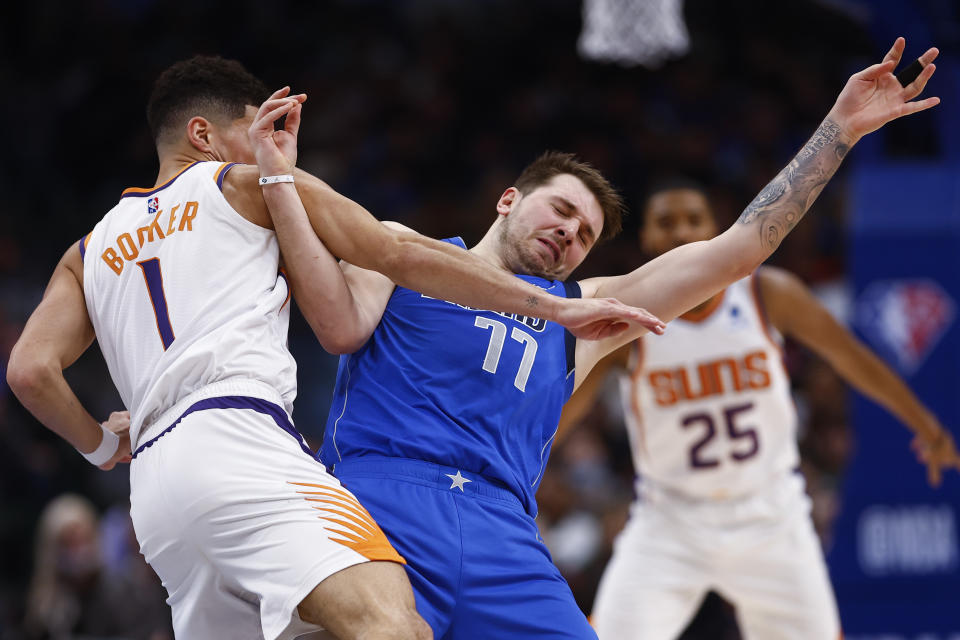 Phoenix Suns guard Devin Booker (1) fouls Dallas Mavericks guard Luka Doncic (77) during the first half of an NBA basketball game, Thursday, Jan. 20, 2022, in Dallas. (AP Photo/Brandon Wade)