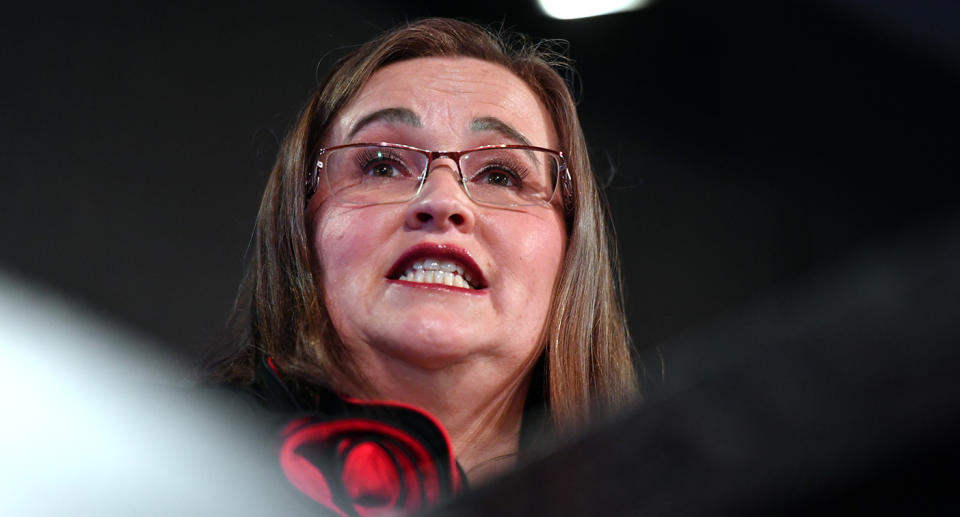 Kate Jenkins wearing glasses with shoulder length brown hair speaking camera looking up towards her