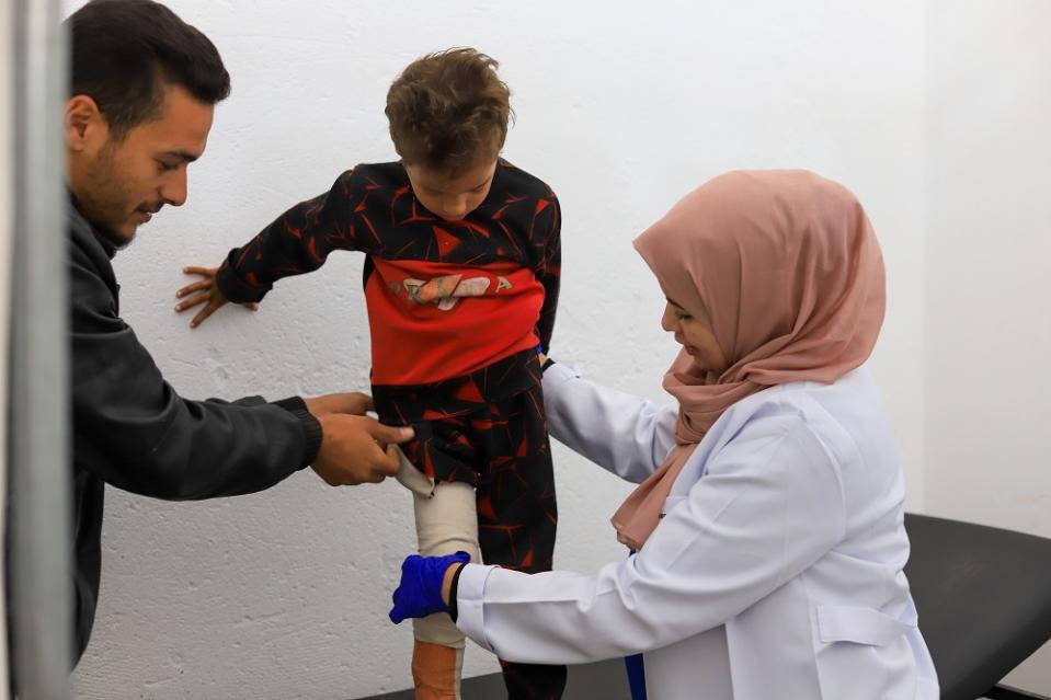 ▲無國界醫生的物理治療師米亞在無國界醫生位於拉法的馬瓦西的醫療站為一名 6 歲男孩進行物理治療，左為男孩的父親。（攝於 2024 年 2 月。© Mariam Abu Dagga）