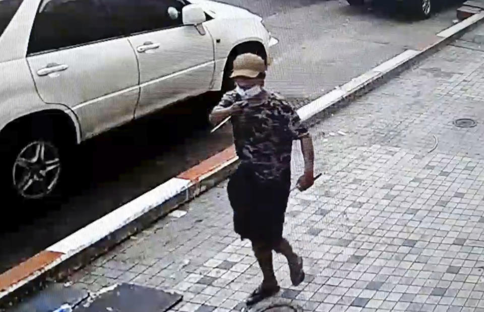 In this image taken from video obtained by Than Lwin Khet News, a man holds a pointed instrument before he attacks an unidentified man on the sidewalk of Sule Pagoda Road in Yangon, Myanmar, Thursday, Feb. 25, 2021. Members of a group supporting Myanmar's military junta have attacked and injured people protesting against the army’s Feb. 1 seizure of power that ousted the elected government of Aung San Suu Kyi. (Than Lwin Thet News via AP)