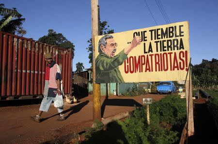 A man walks near a sign with an image of Cuban President Raul Castro in Havana December 19, 2014. REUTERS/Stringer