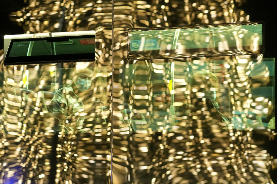 People wearing face masks ride a bus, its windows reflecting a giant Christmas tree, in Lisbon, Monday, Dec. 6, 2021. Despite having one of the highest vaccination rates in Europe, with 86.6% of its 10.3 million people inoculated, Portugal is scaling up its pandemic response amid the emergence of the omicron variant. (AP Photo/Armando Franca)