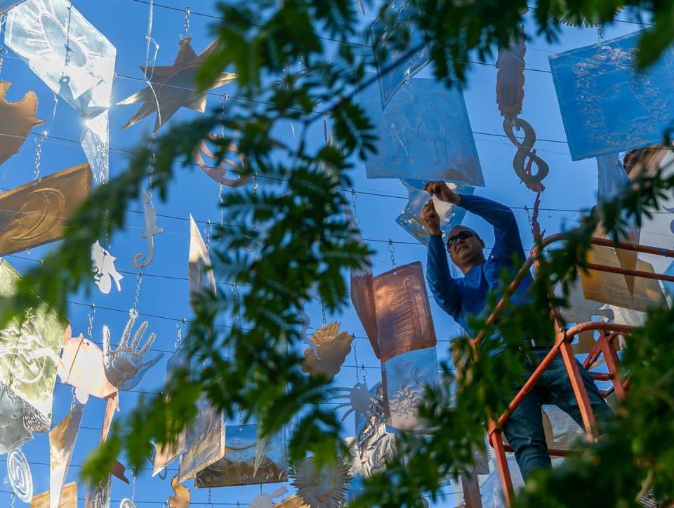 A worker adjusts Carlos Betancourt’s Milagros! art installation.