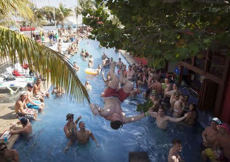 A spring-breaker jumps into a pool during a pool party at a hotel in Cancun March 14, 2015. REUTERS/Victor Ruiz Garcia