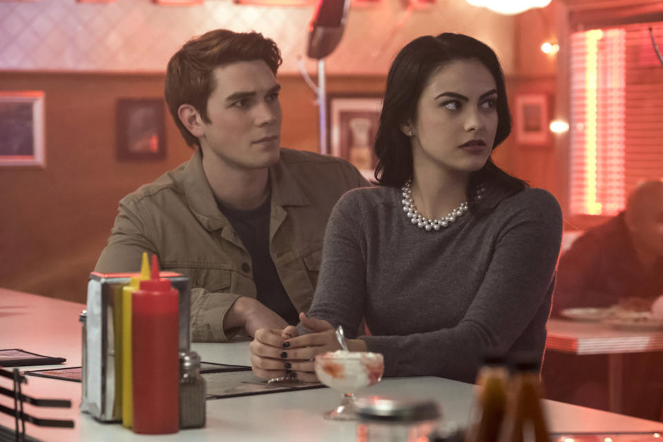 two teens sitting at a dinner looking ahead in a concern