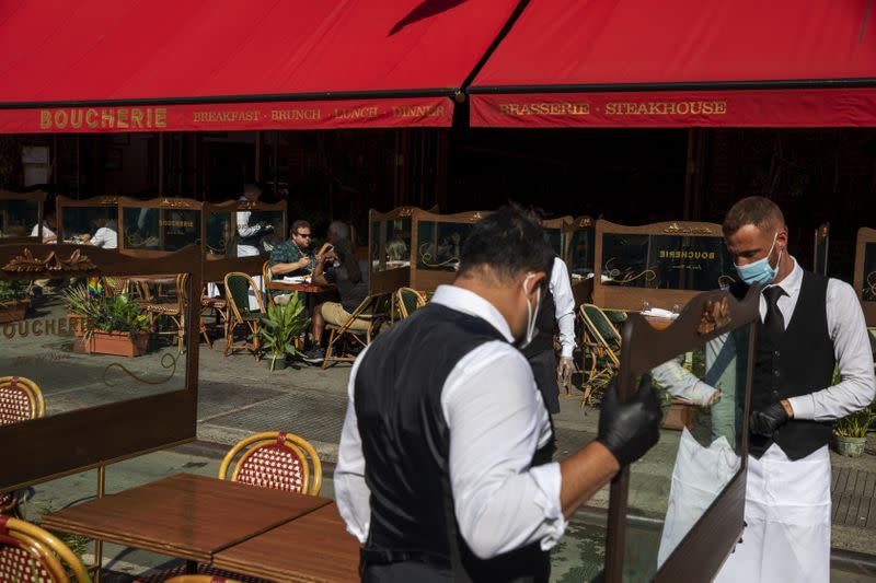 Waiters at a restaurant adjust social distancing screens outside for outdoor seating a restaurant in New York City