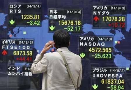 A man looks at an electronic board displaying Japan's Nikkei average (top C) and the stock price indexes of various countries outside a brokerage in Tokyo September 4, 2014. REUTERS/Issei Kato