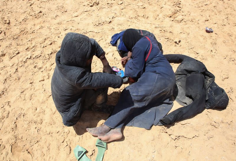 Blessing David, a pregnant 20-year-old woman from Ghana, and her husband rest while they are stranded in the desert on the Libyan-Tunisian border, near Al-Assah