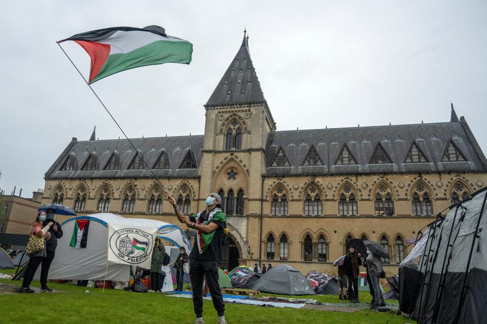 A student activist waves a Palestinian flag at a pro-Palestine encampment at Oxford University (Getty Images)