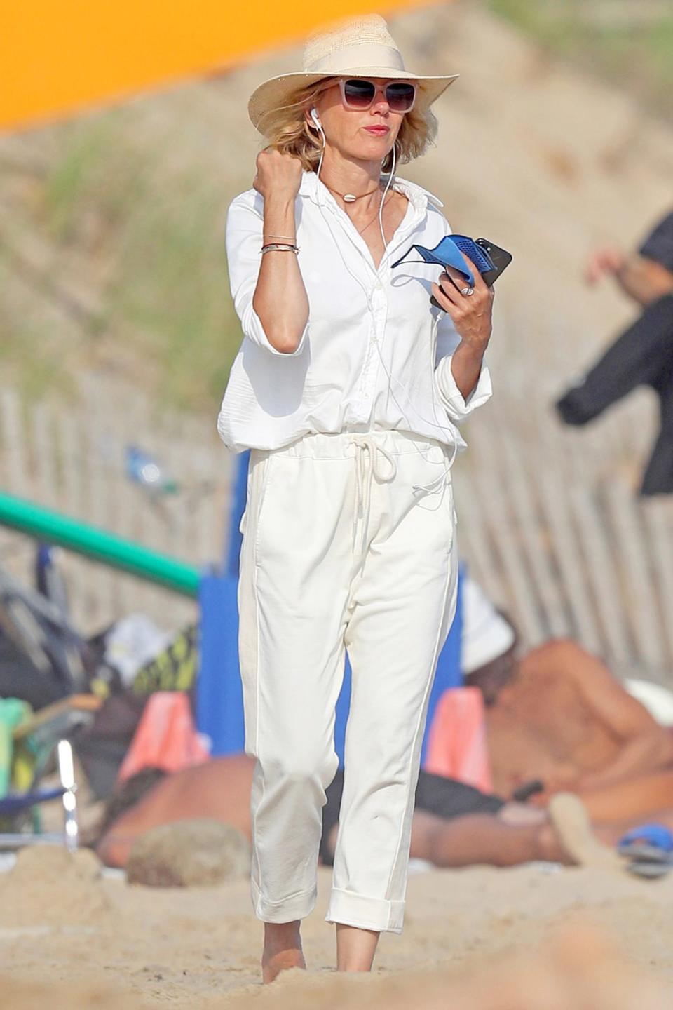 <p>A breezy Naomi Watts walks along the beach in The Hamptons, New York, on Wednesday.</p>
