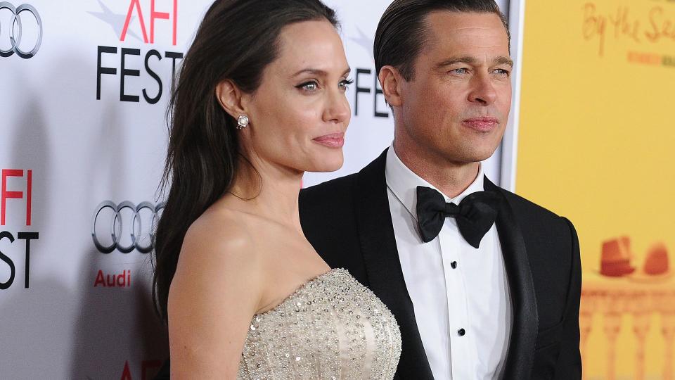 Brad Pitt wearing a black tuxedo and Angelina Jolie wearing a sparkly dress