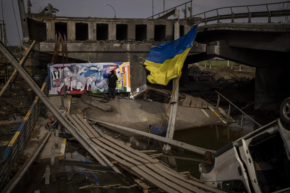 Roberto Marquez, a Mexican artist living in the United States, paints a work inspired by Picasso's canvas of Guernica, the Basque city bombed on 26 April 1937, on a bridge destroyed in Irpin, near Kyiv, on Tuesday, April 26, 2022. (AP Photo/Emilio Morenatti)