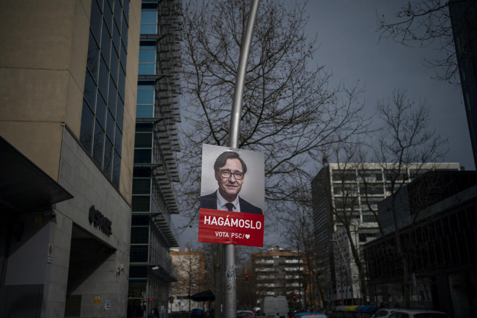 A poster with a photo of Catalan Socialist Party (PSC) candidate in the upcoming Catalan elections Salvador Illa, hangs on a streetlight next to the party headquarter in Barcelona, Spain, Monday, Feb. 8, 2021. A former health minister of Spain hopes to become a quiet political disruptor in the country's Catalonia region when voters go to the polls next weekend. (AP Photo/Emilio Morenatti)