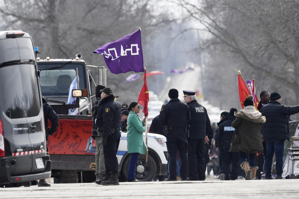 A woman speaks with Ontario Provincial Police officers as she removes flags from a rail blockade in Tyendinaga Mohawk Territory, near Belleville, Ont., on Monday Feb. 24, 2020, during a protest in solidarity with Wet'suwet'en Nation hereditary chiefs attempting to halt construction of a natural gas pipeline on their traditional territories. (Adrian Wyld/The Canadian Press via AP)