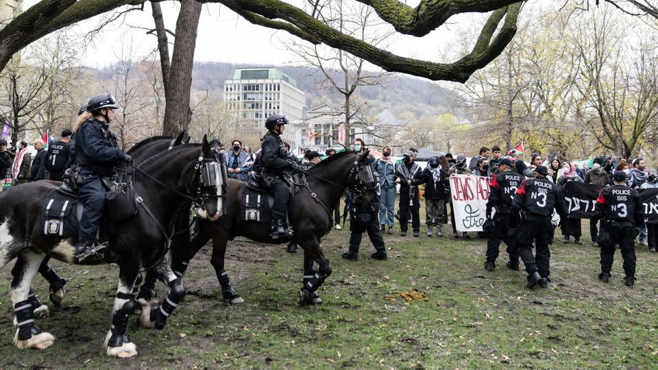 Mounted police officers walk past as pro-Palestinian activists at an encampment set up on McGill University's campus in Montreal, on May 2, 2024. - Christinne Muschi/AP