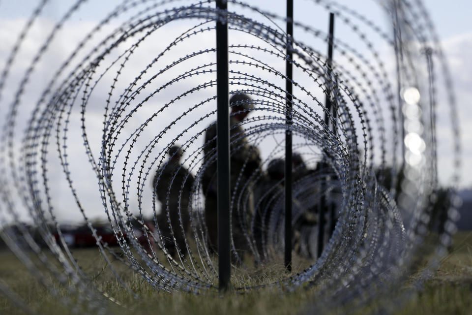 FILE--In this Nov. 3, 2018, file photo, members of the U.S. Army build a razor wire fence around area for tents near the U.S.-Mexico International bridge, in Donna, Texas. The U.S. government is working to open two new large tent facilities to temporarily detain up to 1,000 migrant parents and children near the southern border. U.S. Customs and Border Protection said in a notice to potential contractors that it's seeking to build large tents in El Paso, Texas, and in South Texas that could house 500 people at a time. The notice says families would sleep on mats inside each tent. (AP Photo/Eric Gay, File)