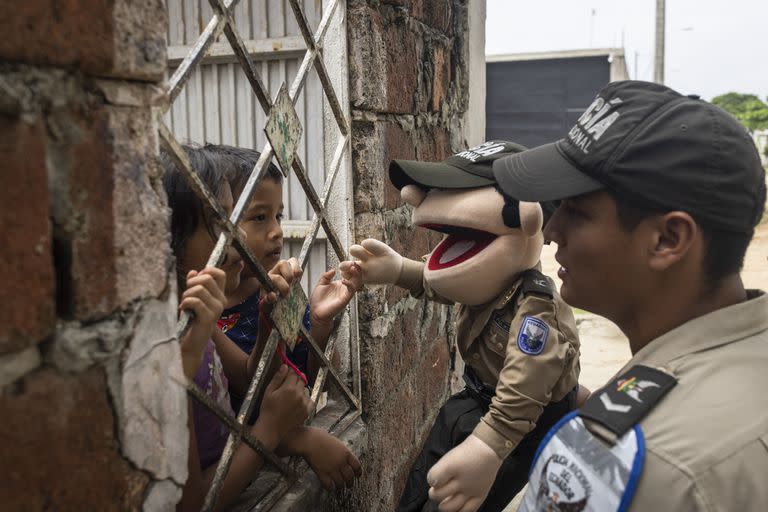 Un miembro de la policía comunitaria de Ecuador enseña a los niños sobre seguridad en un barrio bajo el dominio de grupos criminales vinculados al narcotráfico, en Guayaquil, Ecuador, el 31 de mayo de 2023. Ecuador, en el extremo occidental de Sudamérica, se ha convertido en pocos años en la fiebre del oro del narcotráfico, con grandes cárteles de países tan lejanos como México y Albania uniendo fuerzas con bandas callejeras y carcelarias, desatando una ola de violencia sin precedentes en la historia reciente del país. (Victor Moriyama/The New York Times)