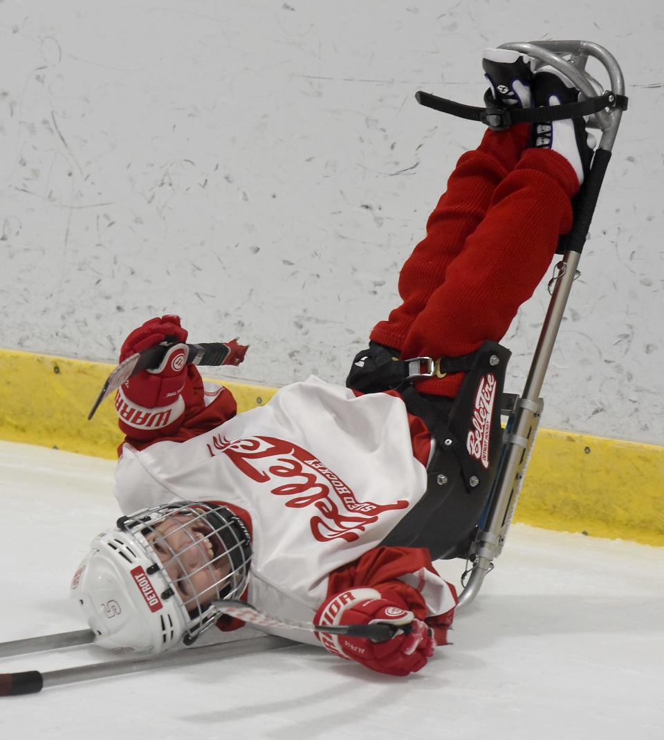 Conner Adcock, 9, (foreground) of Flat Rock laughs hard after he is flipped up on his back on his sled by his dad Steve Adcock at his novice game in the recent tournament Jan. 20, 2024 at Taylor Sportplex.