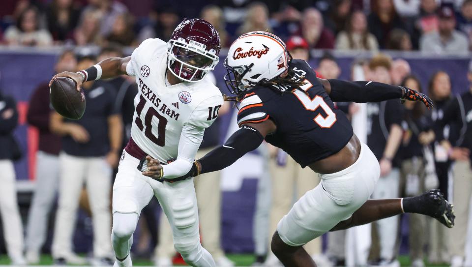 Dec 27, 2023; Houston, TX, USA; Texas A&M Aggies quarterback Marcel Reed (10) scrambles with the ball as Oklahoma State Cowboys safety Kendal Daniels (5) attempts to make a tackle during the first quarter at NRG Stadium. Mandatory Credit: Troy Taormina-USA TODAY Sports