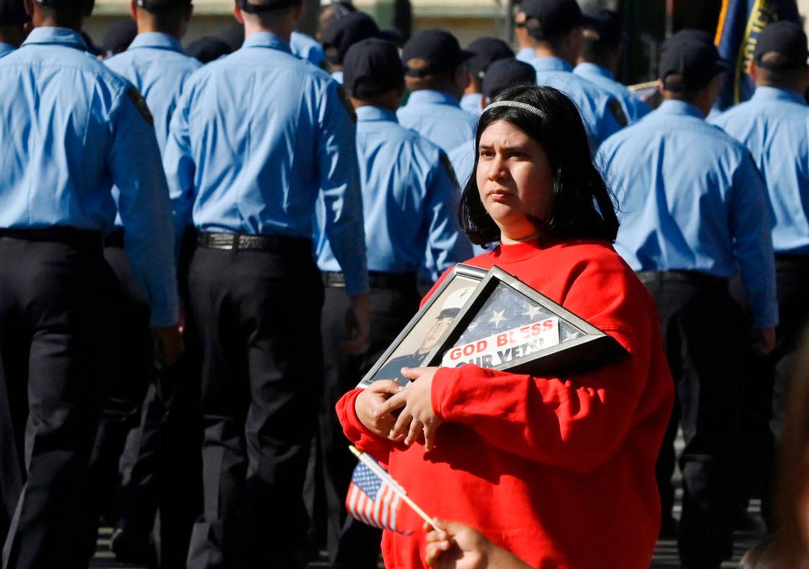 Tracie Real of Fresno holds a framed photo of her uncle Leonard Kienzle who served in the Marine Corps during the Korean War as the annual Central Valley Veterans Day Parade marches by Saturday, Nov. 11, 2023 in downtown Fresno.